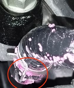 Zbliżenie na przewód z uszkodzeniami i metalowym obejmem, oznaczony czerwonym kółkiem.