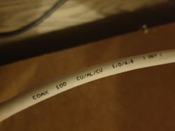 Zbliżenie na kabel koncentryczny z nadrukiem COAX 100 CU/AL/CU.