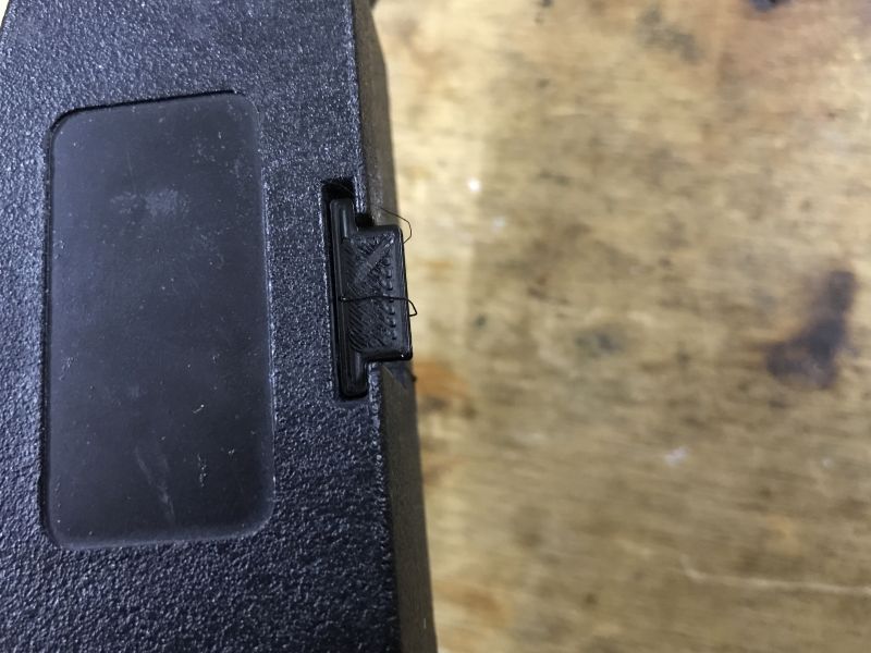 Close-up of a 3D-printed test piece fitted into a black enclosure on a wooden surface