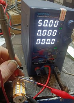 Programowalny zasilacz DC ustawiony na 50V z podłączonymi przewodami do diod LED.