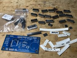 Set of electronic components and a blue PCB on a table.