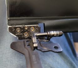 Zbliżenie na uszkodzony zawias w laptopie przy klapce matrycy.