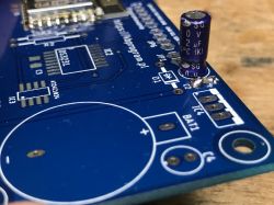 PCB with a soldered capacitor and placeholder for components.