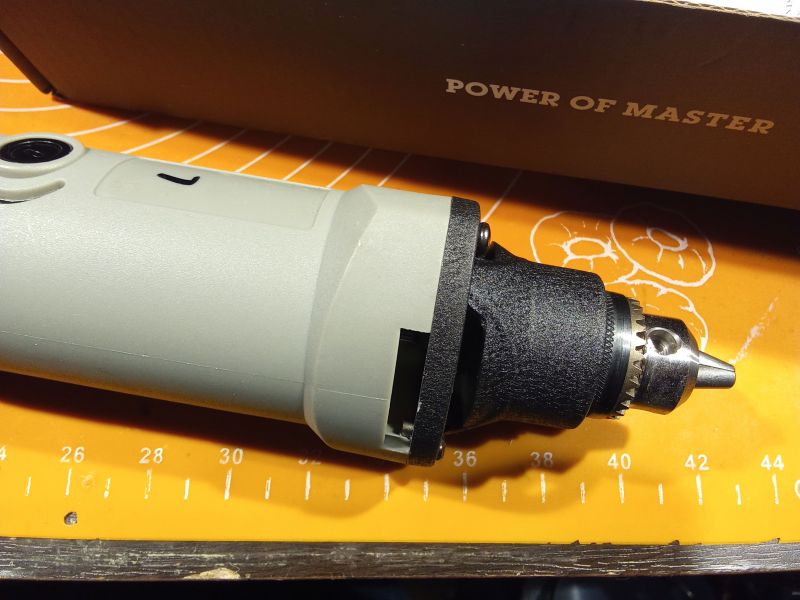 Elektronarzędzie z uchwytem wiertarskim na tle pomarańczowej maty.