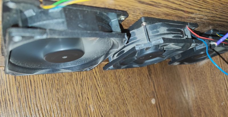 Fans Mounted Under Table View of three mounted computer fans under a wooden table.