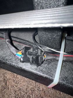 Nahaufnahme eines schwarzen Kabelsteckers mit bunten Drähten und Kabelbinder