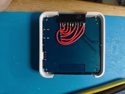Printed circuit board with connected red wires in a white case.