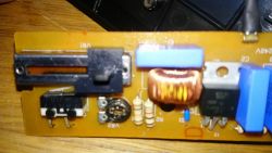 Zbliżenie na płytkę drukowaną z elementami elektronicznymi, w tym potencjometrem suwakowym, cewką i opornikami.