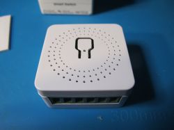 Mini smart switch in a white casing with a perforated pattern.