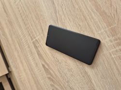 Smartfon z wygaszonym ekranem leży na drewnianym blacie, widok z góry