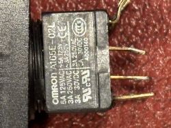 Widok zbliżony na tylną część przycisku Omron A165E-02L z trzema widocznymi pinami.