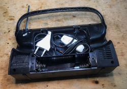 Radio Battery Compartment with Power Cord and Switch Open battery compartment of an old radio with a power cord and a switch stored inside.