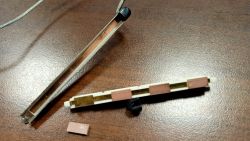 Rozłożony przetwornik piezoelektryczny do gitary basowej z widocznymi płytkami piezoelektrycznymi i metalową obudową.