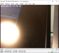 Man sitting in front of a webcam, looking at a monitor with a focused expression.