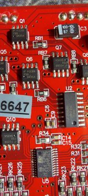 Zbliżenie na czerwony obwód drukowany z różnymi układami scalonymi i komponentami elektronicznymi.