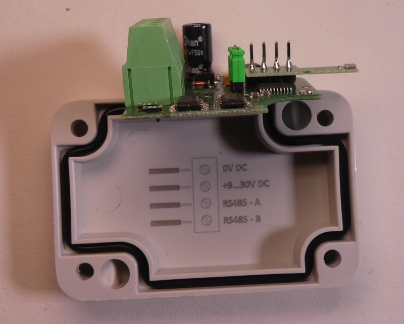 Moduł elektroniczny z odkrytą obudową i oznaczeniami wyprowadzeń.