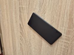 Czarny smartfon z wyłączonym ekranem oparty o drewnianą powierzchnię