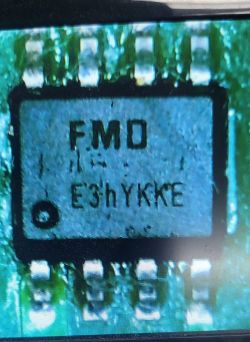 Zbliżenie układu scalonego z oznaczeniem FMD E3h YKKE na zielonej płytce PCB