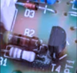 Close-up of a circuit board with a resistor labeled R2 and other electronic components.