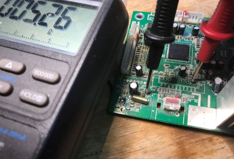 Multimeter measuring resistance on a PCB with two probes connected to the circuit