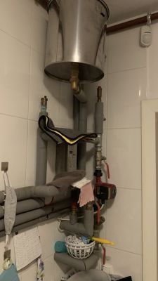 Instalacja hydrauliczna z metalowym zbiornikiem i rurami w małym pomieszczeniu