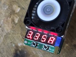 USB tester with LED display showing 3.15A and a visible cooling fan on top.