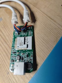 Close-up of a circuit board with two white cables, a microphone, and electronic components.