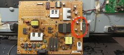 Płyta drukowana o brązowym kolorze z różnymi elementami elektronicznymi i zaznaczonym na czerwono złączem po prawej stronie.