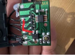 Zbliżenie na zieloną płytkę drukowaną z podzespołami elektronicznymi i czerwoną strzałką.