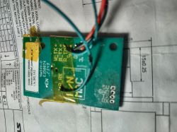 Green PCB with attached wires, placed on a technical drawing sheet.