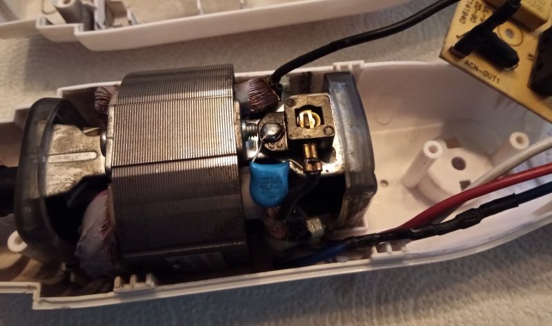 Widok wnętrza rozebranego blendera z widocznym silnikiem szczotkowym oraz przewodami i podzespołami elektrycznymi.