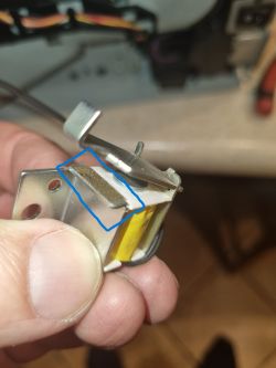 Zbliżenie na metalowy element z filcem zaznaczonym na niebiesko, trzymany w palcach.