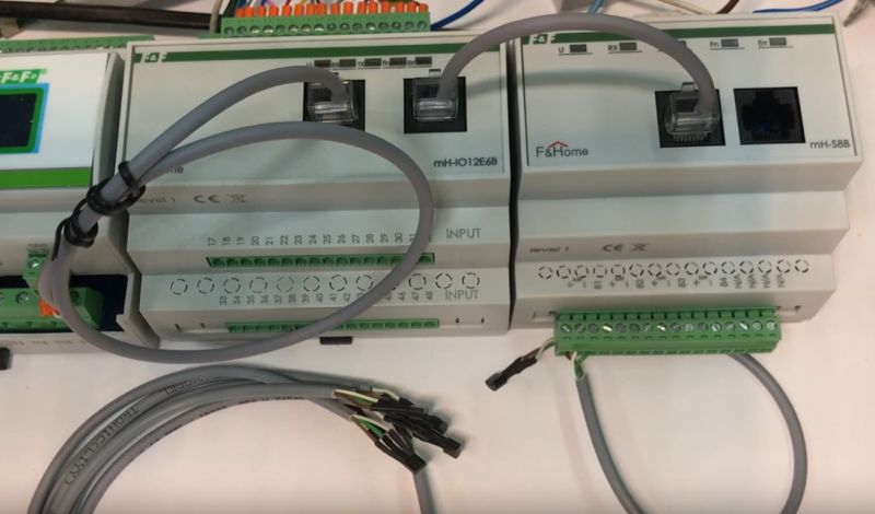 F&amp;Home building automation modules on DIN rail with connected wires and visible input/output terminals.