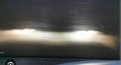 Światła samochodowe rzucone na garażową bramę z wyraźnym poziomym cutoffem DOT