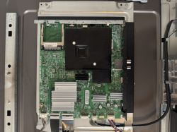 TV Mainboard with Heatsinks and Connectors Television mainboard mounted on a metal frame with visible heatsinks and connectors.