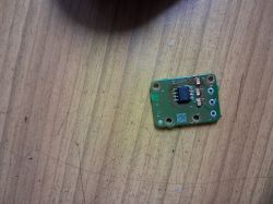 Mała zielona płytka PCB z układem scalonym i otworami montażowymi na drewnianym blacie