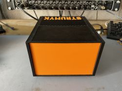 Black electronic device with orange front panel and “STRUMYK” label on top