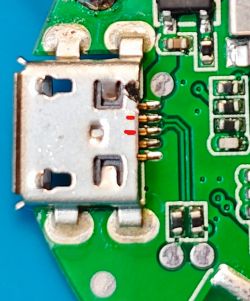 Micro USB connector soldered to a green PCB with visible pins and burn marks near the pins.