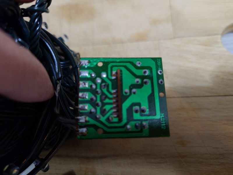 Zielona płytka PCB sterownika lampek z widocznymi ścieżkami i przewodami po lewej