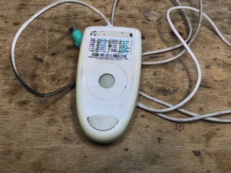 Old Trekker Ball Mouse with PS/2 Connector Old Trekker ball mouse with visible cable and PS/2 connector on a wooden table.