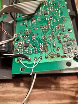 Zbliżenie na zieloną płytkę z układem elektronicznym, widoczne różne elementy i przewody.