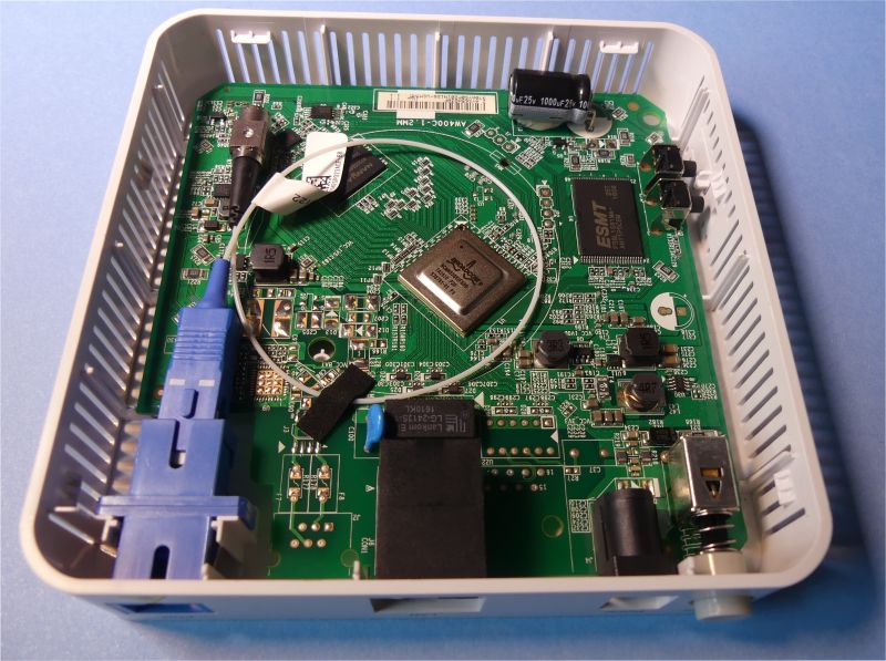 Wnętrze urządzenia GPON ONT z widoczną płytą główną, pigtailami optycznymi, złączem SC oraz układami scalonymi.