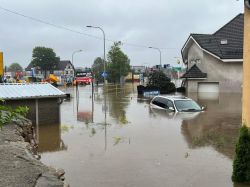 Zalane ulice z samochodem częściowo zanurzonym w wodzie.