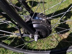 Silnik rowerowy zamontowany na tylnym kole roweru z widocznymi szprychami.