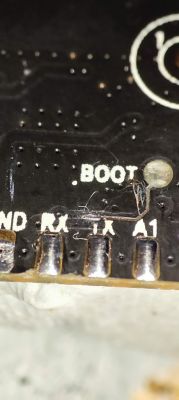 Close-up of a PCB with exposed copper trace near the .BOOT label.