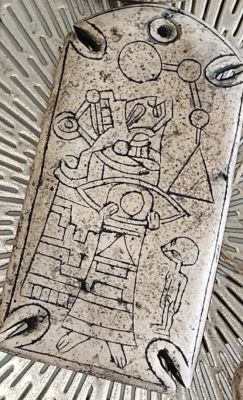 Kamienny artefakt z wyrytym humanoidem, piramidą i symbolami geometrycznymi