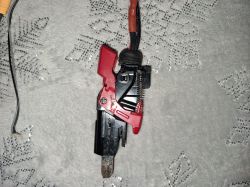 Zbliżenie na mechanizm przycisku z czerwonym elementem, umieszczony na teksturowanym tle.