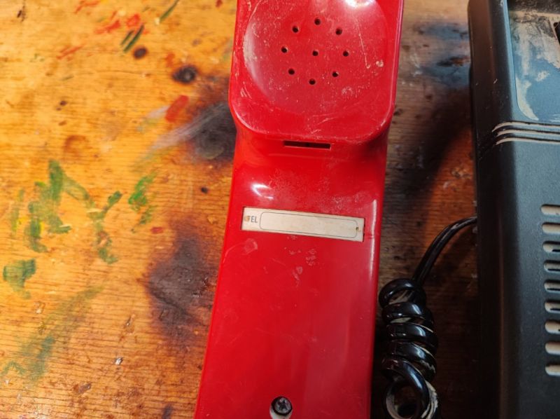 Czerwona słuchawka starszego telefonu z lat 90. na drewnianym stole