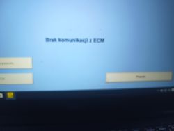 Rozmazany ekran komputera z komunikatem „Brak komunikacji z ECM”