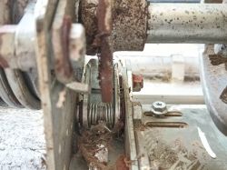 Zbliżenie na mechanizm z widocznym sprężyną i gwoździem blokującym.